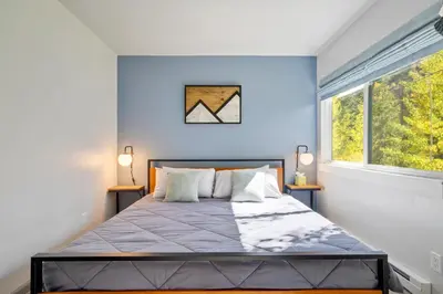 a bedroom with a bed with blue walls and a window at Soda Springs Ski Retreat - Heated Pool & Hot Tub in Keystone
