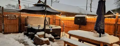 a snow covered backyard with a hot tub and an umbrella at Pet Friendly Suite with Fenced Garden, HotTub, Sauna in Denver