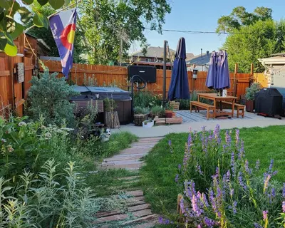 a garden with umbrellas and a table and a fence at Pet Friendly Suite with Fenced Garden, HotTub, Sauna in Denver