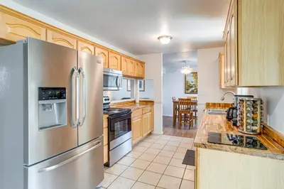 a kitchen with a stainless steel refrigerator and wooden cabinets at 2 Mi to Hospitals Home with Private Yard in Aurora in Aurora