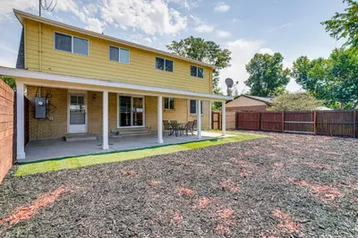 a yellow house with a patio and a fence at 2 Mi to Hospitals Home with Private Yard in Aurora in Aurora