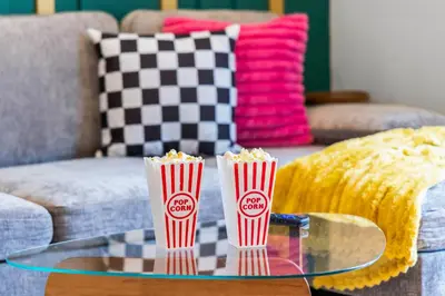 two cups of popcorn on a glass table on a couch at Olde Town Gem 5 TVs Hot Tub & Game Yard in Arvada