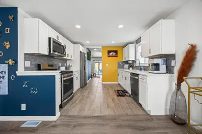 a kitchen with white cabinets and a blue wall at Olde Town Gem 5 TVs Hot Tub & Game Yard in Arvada