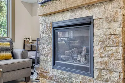 a stone fireplace in a living room with a couch at 1820 The Seasons condo in Keystone
