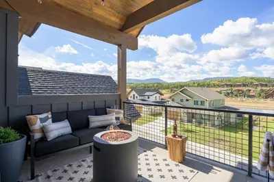 a patio with a couch and a table on a balcony at Lodge 212 Brand New LUXE Designer Home and Hot Tub in Fraser