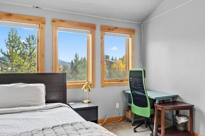a bedroom with a bed and a desk and windows at Mountain Getaway Deck Spacious Kitchen in Silverthorne