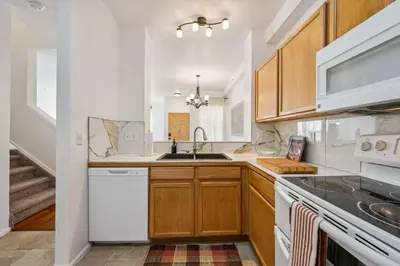 a kitchen with white appliances and wooden cabinets at 3BR Modern Retreat, Close to DIA & Downtown Denver in Commerce City