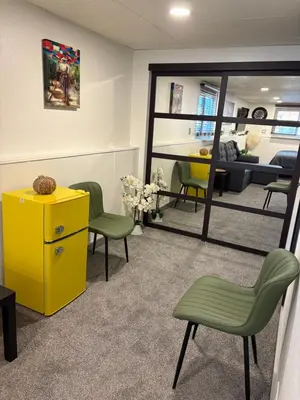 a waiting room with a yellow cabinet and green chairs at The Cozy nest in Englewood