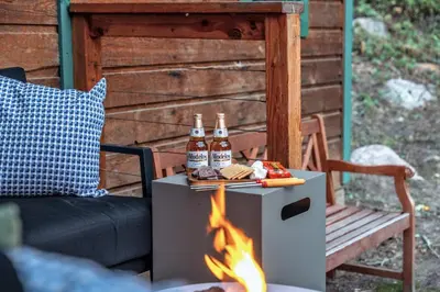 two bottles of beer on a table next to a fire at Dog Friendly, Year Round, Creekside Cabin, Hot Tub, 6 Acres in Jamestown