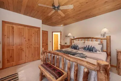 a bedroom with a wooden bed and a ceiling fan at Granby Panoramic Paradise! Hot tub and firepit! in Granby