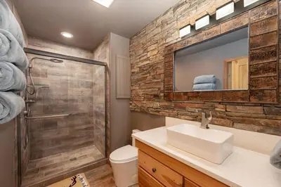 a bathroom with a sink and a shower and a mirror at Granby Panoramic Paradise! Hot tub and firepit! in Granby