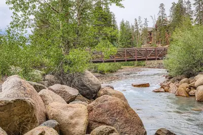 a bridge over a river with rocks and trees at 305 Brightwood at Keystone condo in Keystone