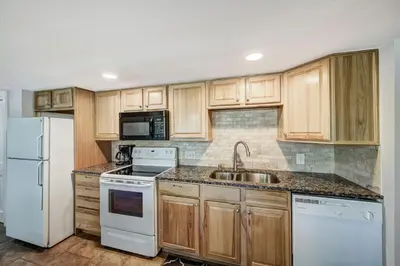 a kitchen with white appliances and wooden cabinets at Keystone Mtn Getaway - Cozy Condo for 4 in Keystone