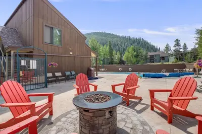 a patio with four red chairs and a fire pit at Keystone Mtn Getaway - Cozy Condo for 4 in Keystone