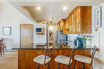 a kitchen with a counter with chairs in it at Timber Ridge Escape in Silverthorne