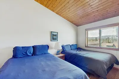two blue beds in a room with a window at Riverview Condo #4 in Grand Lake