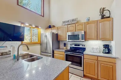a kitchen with stainless steel appliances and wooden cabinets at Riverview Condo #4 in Grand Lake