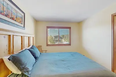 a bedroom with a blue bed with a window at Riverview Condo #4 in Grand Lake
