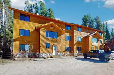 a large wooden house with a truck parked in front of it at Riverview Condo #4 in Grand Lake