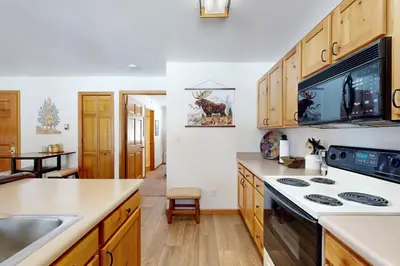 a kitchen with wooden cabinets and a stove top oven at Riverview Condo #5 in Grand Lake