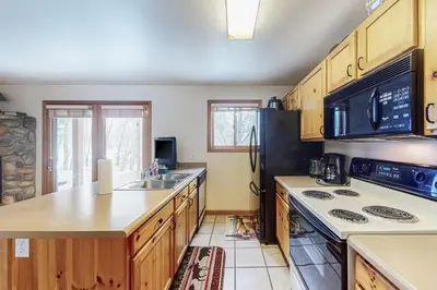 a kitchen with wooden cabinets and a stove top oven at Riverview Condo #7 in Grand Lake