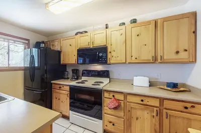 a kitchen with wooden cabinets and a black refrigerator at Riverview Condo #7 in Grand Lake