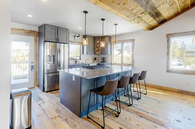 a kitchen with a large island with bar stools at Square House in Grand Lake