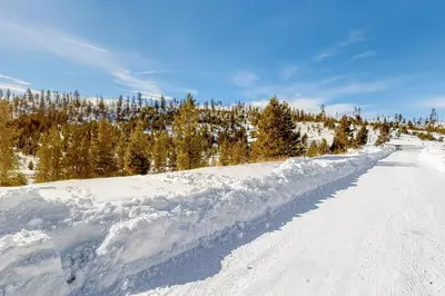 a snow covered road with trees in the background at Square House in Grand Lake