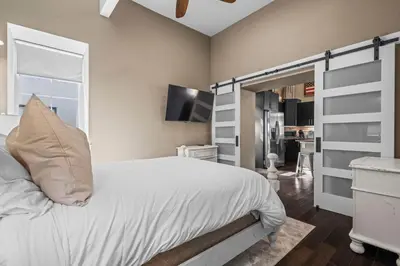a bedroom with a white bed and a kitchen at Stylish Church Conversion Walk to LoHi in Denver