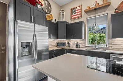 a kitchen with black cabinets and a stainless steel refrigerator at Stylish Church Conversion Walk to LoHi in Denver