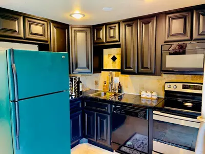 a kitchen with wooden cabinets and a blue refrigerator at Getaway Spot Close To Red Rocks, Denver & Mtns in Lakewood
