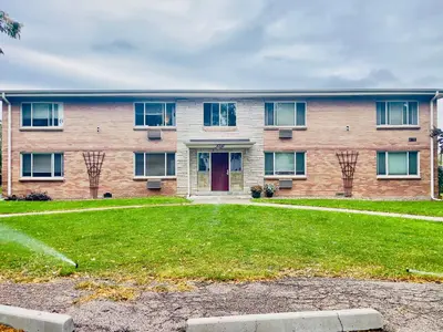 a brick building with a red door and a yard at Getaway Spot Close To Red Rocks, Denver & Mtns in Lakewood