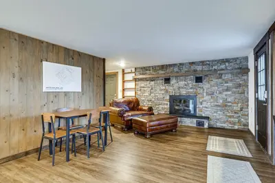 a living room with a stone fireplace and a table and chairs at Grand Family Home with Deck and Trail Access in Fraser in Fraser
