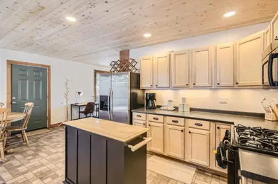 a large kitchen with wooden cabinets and a table at Cozy Wolfcamp Chalet with Hot Tub, Views with Fast Wifi in Bailey
