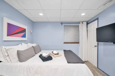 a bedroom with a bed with a tv on the wall at The Lux in Lakewood. Minutes from Red Rocks. Hikes in Lakewood