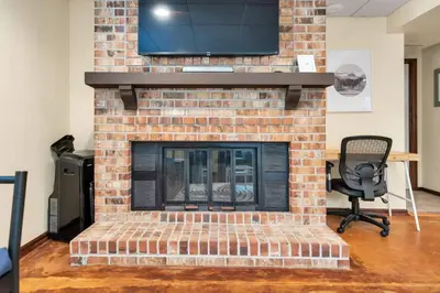 a brick fireplace with a tv on top of it at The Lux in Lakewood. Minutes from Red Rocks. Hikes in Lakewood