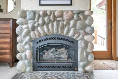 a living room with a stone fire place at Hide-A-Way. Private Hot Tub Pets Welcome. in Evergreen