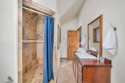 a bathroom with a shower and a sink and a mirror at Hide-A-Way. Private Hot Tub Pets Welcome. in Evergreen
