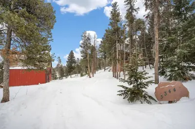 a snow covered road with trees and a red fence at The Tyrolean Cabin. Panoramic Views. Hot Tub. in Golden