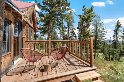 a deck with two chairs on a house at The Tyrolean Cabin. Panoramic Views. Hot Tub. in Golden
