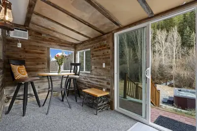 a screened in porch with a table and chairs at Cabin by North Clear Creek. Private Hot Tub. Pets in Black Hawk