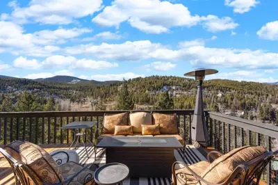 a patio with a table and chairs on a balcony at New. Top of the World Lodge. Hot tub. Theater. in Evergreen