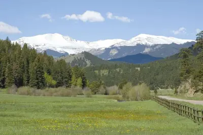 a field with snow capped mountains in the background at New. Top of the World Lodge. Hot tub. Theater. in Evergreen