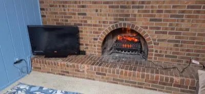 a brick fireplace with a television on top of it at Tiki Bar in The Basement in Arvada