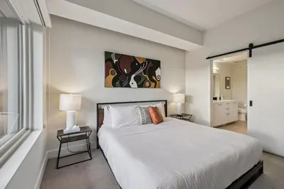 a bedroom with a large white bed and a bathroom at The Espadin LoHi Collection in Denver