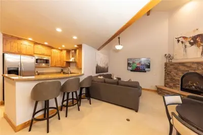 a living room with a couch and a kitchen with a fireplace at 24 Autumn Brook townhouse in Dillon