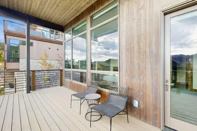two chairs and a table on a deck with windows at Lakota Northwoods Luxury Villa 308 in Winter Park