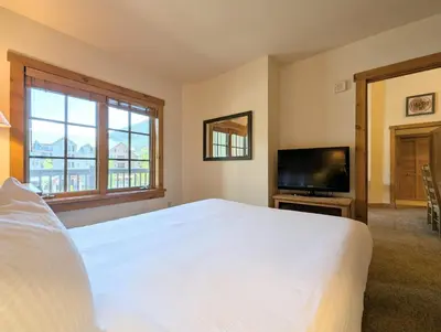 a bedroom with a large white bed and a flat screen tv at Expedition Station 8635 by SummitCove Lodging in Keystone