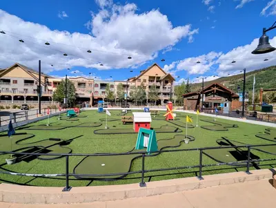 an outdoor playground with a green field with play equipment at Expedition Station 8635 by SummitCove Lodging in Keystone