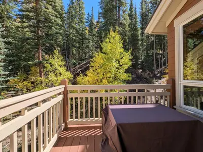 a balcony with a table and a view of the forest at Settlers Creek 6529 by SummitCove Lodging in Keystone